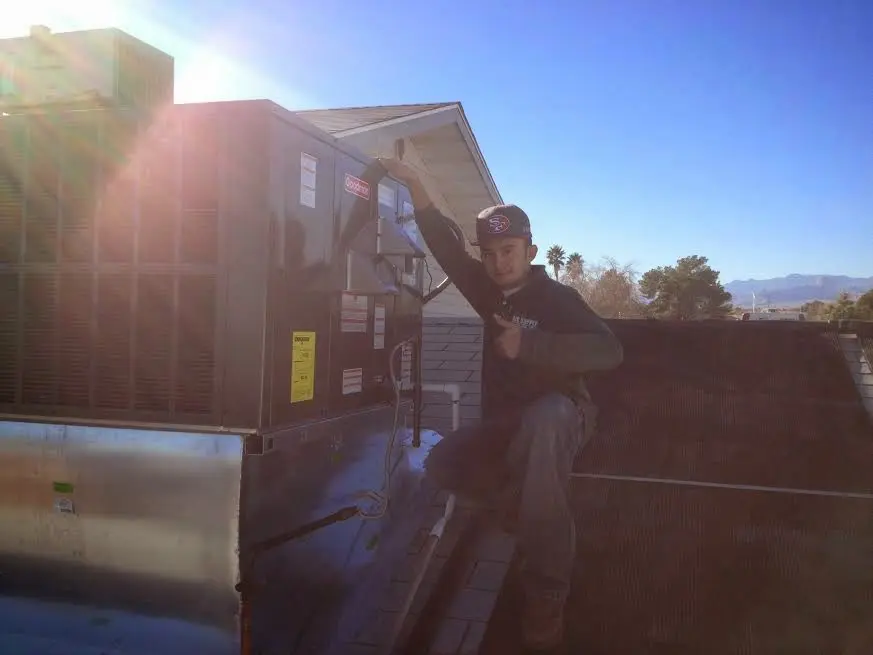 HVAC technician performing AC Tune-Up on a rooftop unit in Monticello